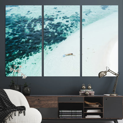 Canvas featuring an aerial view of a swimmer in shallow turquoise waters with coral patterns, ideal for tropical coastal home decor.