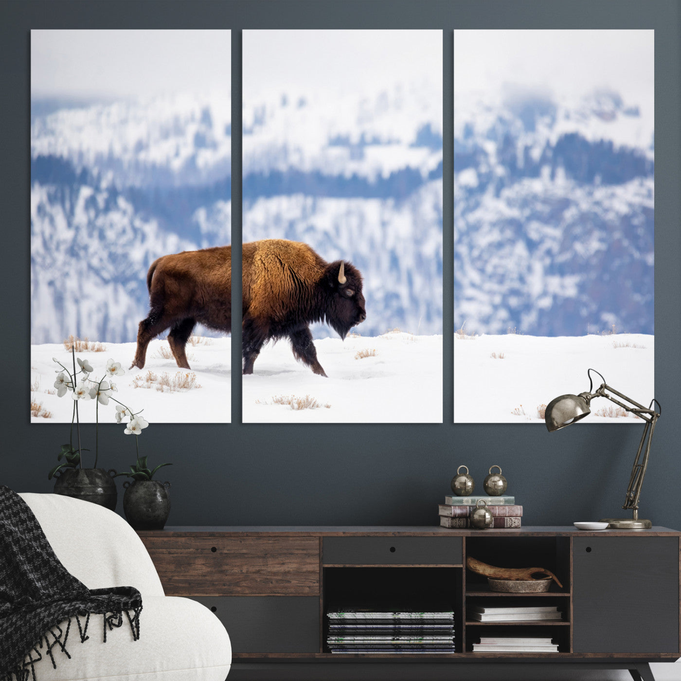 A lone bison walks across snowy ground with blue-toned mountain range behind, ideal for rustic or western farmhouse interiors.