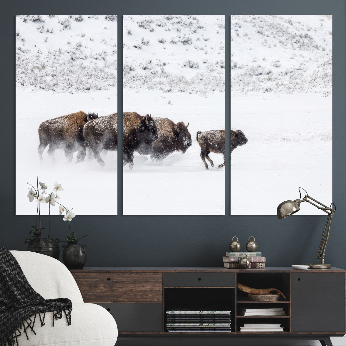Bison herd running through a snowy open field with mountain backdrop, perfect for rustic or western-themed wall decoration.