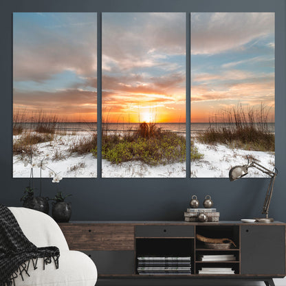 A tranquil beach scene featuring golden sunset hues over the water, with grasses in the foreground and a peaceful, serene atmosphere.