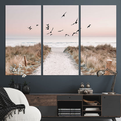 A peaceful coastal pathway leading to the ocean, with birds flying across a soft pastel sky, creating a calm and scenic beach atmosphere.