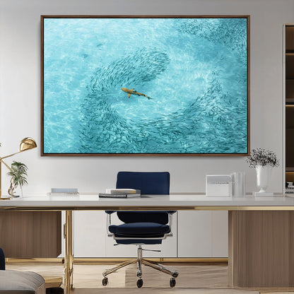 Aerial view of a shark swimming through a swirl of fish in clear turquoise waters, perfect for calm coastal or beach house decor.
