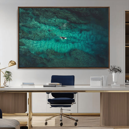 An aerial view of a solo surfer paddling through crystal-clear turquoise waters over a sunlit reef, capturing the beauty and serenity of open water surfing.