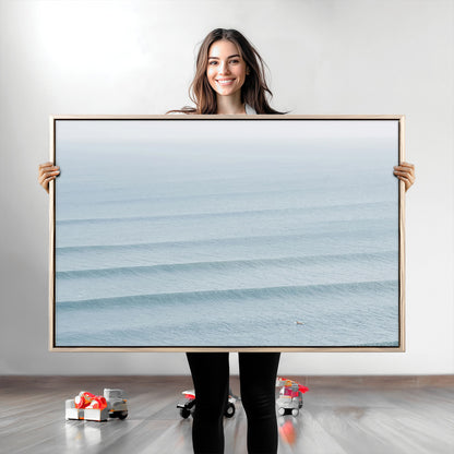 Framed canvas of repeating ocean waves with a distant solo surfer, ideal for minimalist ocean or calm coastal wall decor.
