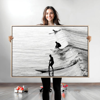 Black and white photo of surfers riding waves in a moody, high-contrast scene, ideal for modern coastal or surf-inspired home decor.