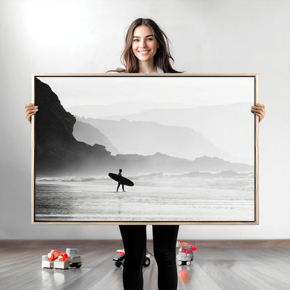 A lone surfer walking along a misty beach with cliffs in the background, carrying their board, capturing a serene and minimal ocean moment.