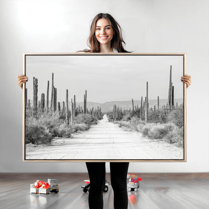 A black and white desert road stretching through a cactus-filled landscape, creating a rugged and timeless southwestern aesthetic with a sense of adventure.