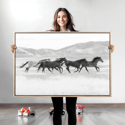 A black and white image of wild horses running freely across an open grassland, capturing the power and beauty of untamed nature in a rustic western setting.