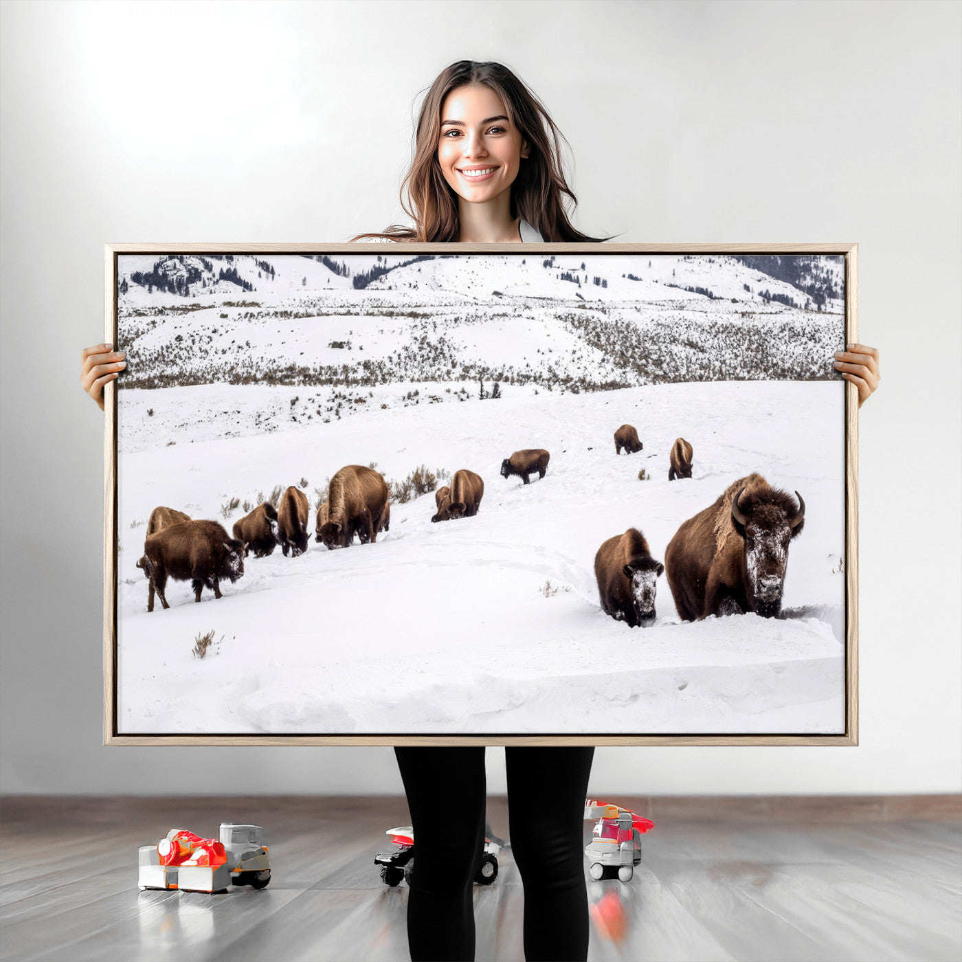 A herd of bison walking through deep snow in a mountain valley, perfect for rustic, cabin or western-themed wall decor.