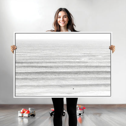 Monochrome photo of a lone surfer in calm layered waves, perfect for minimalist coastal or moody ocean-inspired wall decoration.