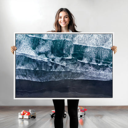Canvas of aerial ocean waves crashing onto a black sand beach in moody tones, ideal for modern coastal or minimalist home decor.