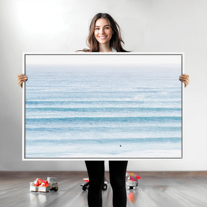 Minimalist ocean view with soft blue waves and a lone surfer, creating a serene and airy coastal aesthetic, perfect for tranquil home decor.