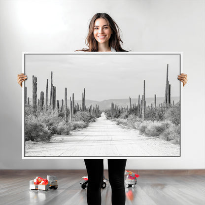 A black and white desert road stretching through a cactus-filled landscape, creating a rugged and timeless southwestern aesthetic with a sense of adventure.