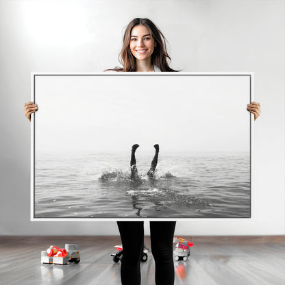 A black and white minimalist water scene capturing a playful splash as a swimmer dives upside down, creating a carefree and artistic aquatic aesthetic.