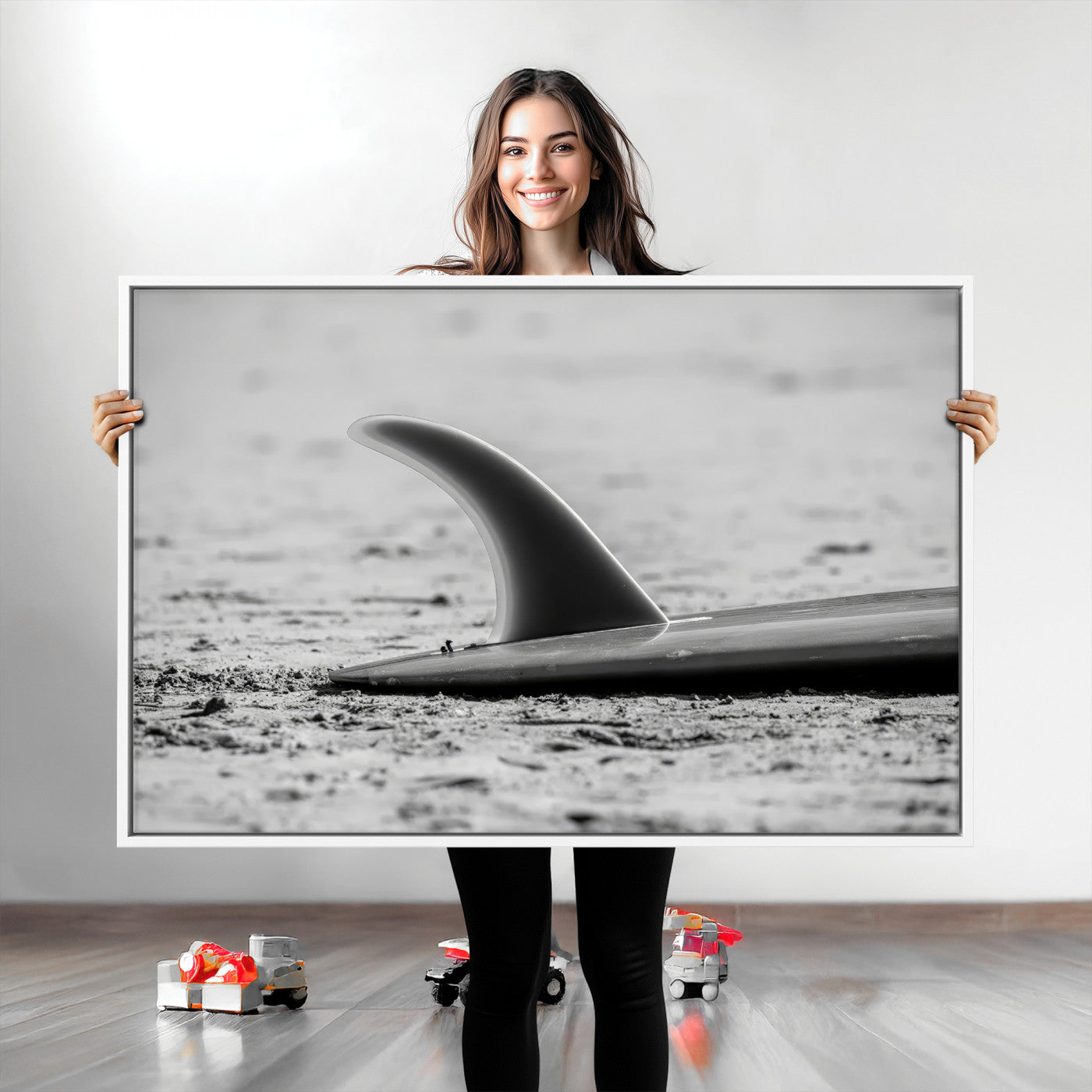 A black and white close-up of a surfboard fin resting on the sandy shore, highlighting minimalist beach aesthetics and classic surf culture.