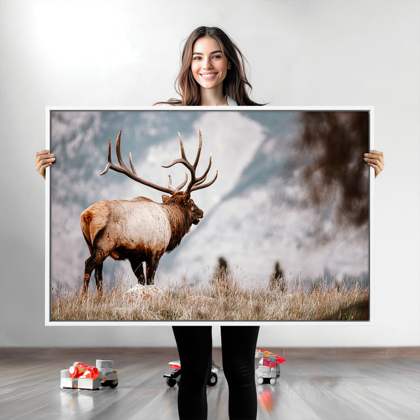 Majestic elk with large antlers standing in grass with snowy mountains in background, perfect for rustic cabin or lodge style decor.
