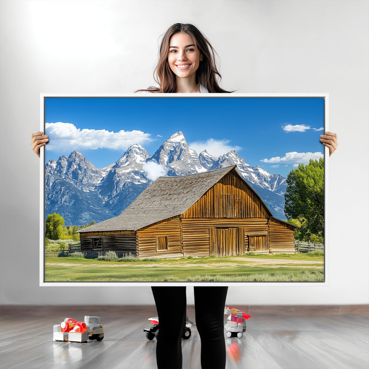 A rustic wooden barn sits in front of towering mountain peaks under a clear blue sky, perfect for farmhouse or cabin style interiors.