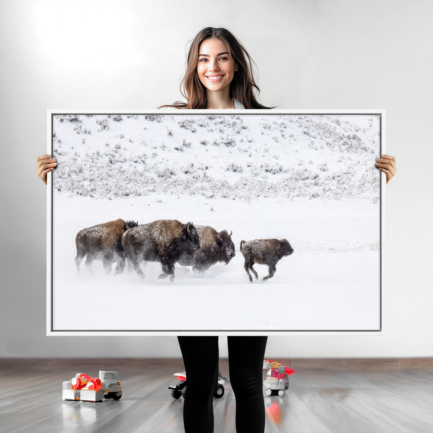Bison herd running through a snowy open field with mountain backdrop, perfect for rustic or western-themed wall decoration.