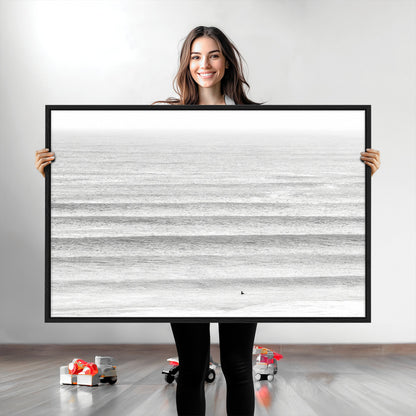 Monochrome photo of a lone surfer in calm layered waves, perfect for minimalist coastal or moody ocean-inspired wall decoration.