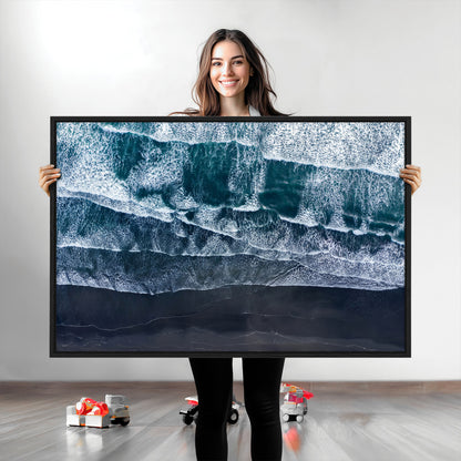 Canvas of aerial ocean waves crashing onto a black sand beach in moody tones, ideal for modern coastal or minimalist home decor.