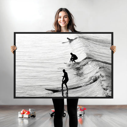 Black and white photo of surfers riding waves in a moody, high-contrast scene, ideal for modern coastal or surf-inspired home decor.
