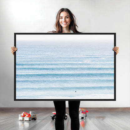 Minimalist ocean view with soft blue waves and a lone surfer, creating a serene and airy coastal aesthetic, perfect for tranquil home decor.