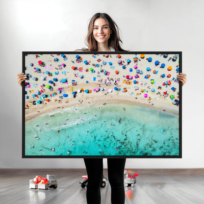Aerial view of a vibrant beach filled with colorful umbrellas and people enjoying the turquoise ocean, capturing a lively summer vacation scene.