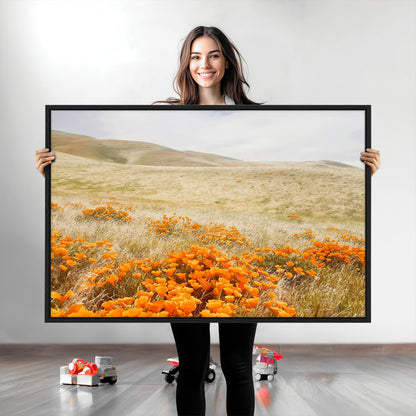 A golden field with vibrant orange poppies blooming across rolling hills under a soft, sunlit sky, creating a warm and rustic landscape.