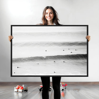A monochrome photograph of swimmers gliding through gentle ocean waves, evoking a sense of calm and movement.