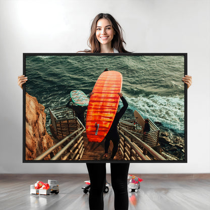 A surfer carrying a bold orange surfboard down a rugged staircase toward the ocean, bathed in golden hour light, capturing the energy of coastal adventure.