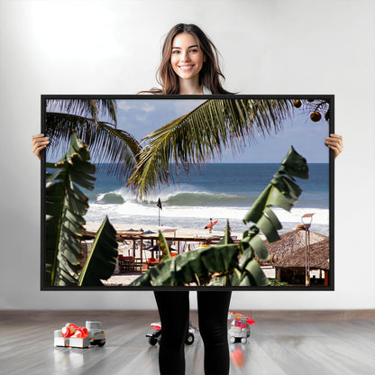 Canvas wall art of a tropical surf scene framed by palm trees, with a surfer on the shore and waves rolling in, ideal for beach-themed decor.