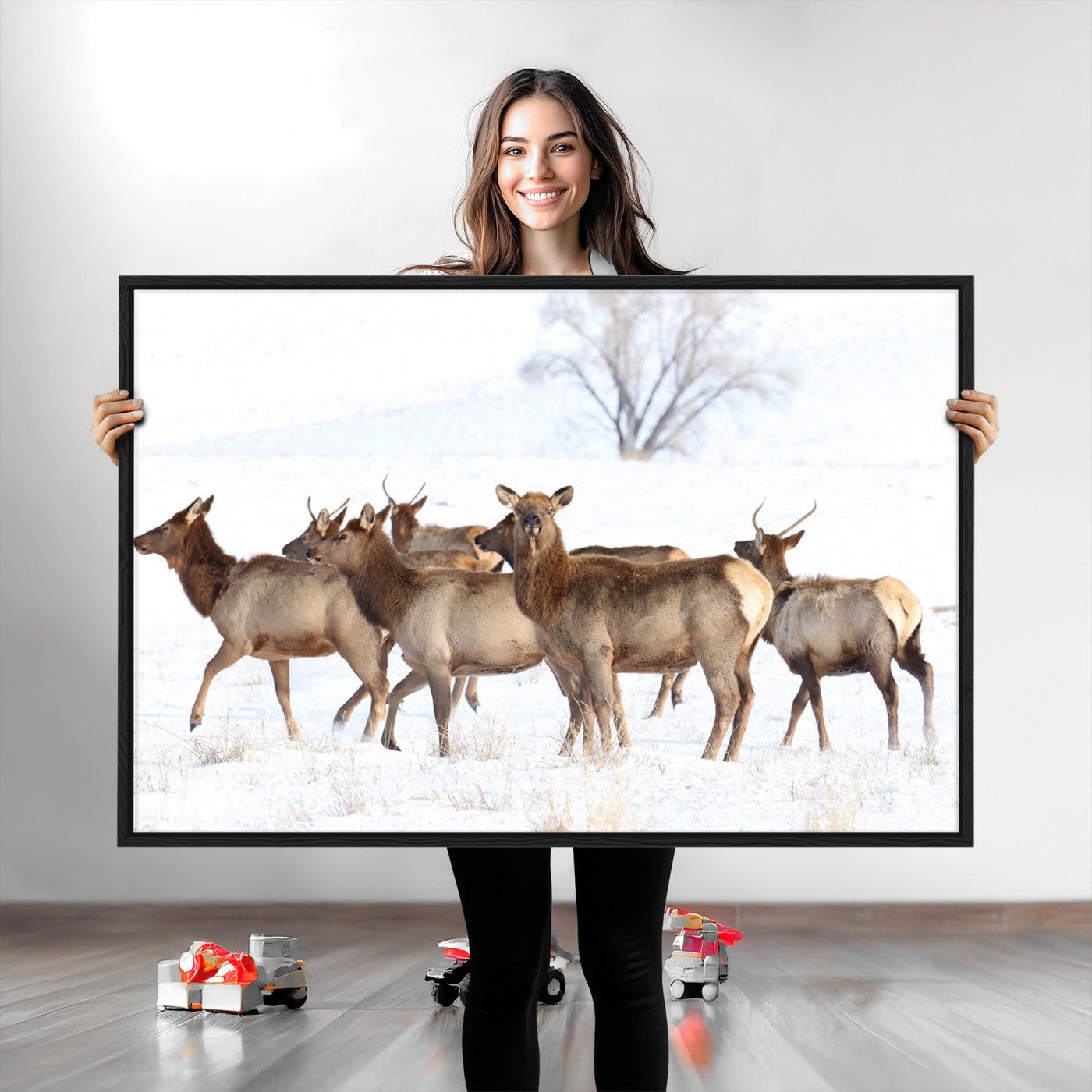 A group of elk standing on snowy terrain with a tree in the background, perfect for rustic or lodge-style winter wall decor.