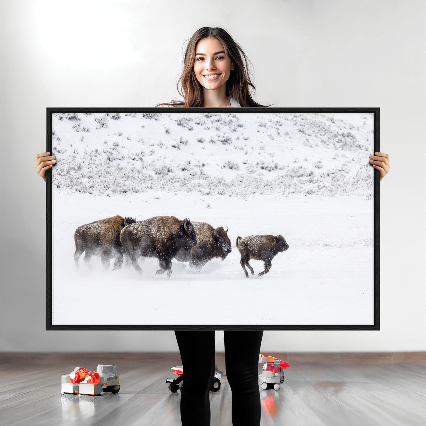 Bison herd running through a snowy open field with mountain backdrop, perfect for rustic or western-themed wall decoration.