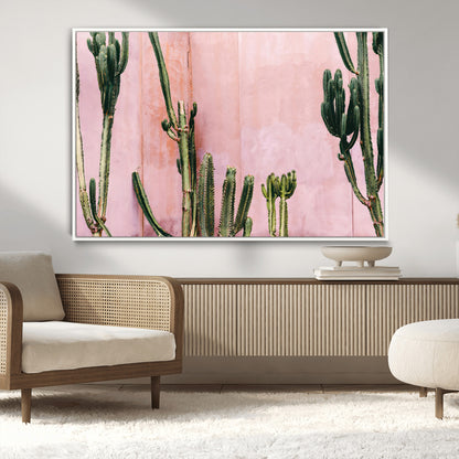 Framed canvas of tall green cacti against a soft pink wall, ideal for modern desert or colorful southwest-inspired home decor.