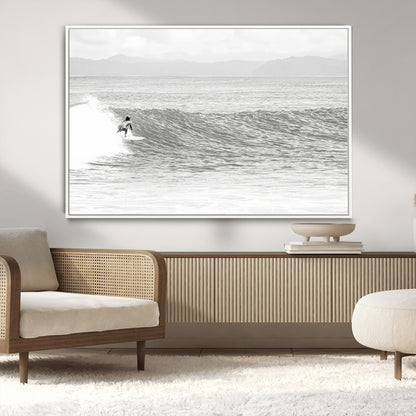 Monochrome photo of a surfer riding a wave with distant mountains, ideal for coastal motion or black and white surf-themed wall decor.