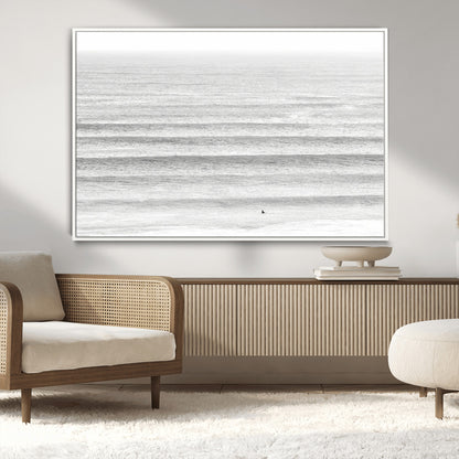 Monochrome photo of a lone surfer in calm layered waves, perfect for minimalist coastal or moody ocean-inspired wall decoration.