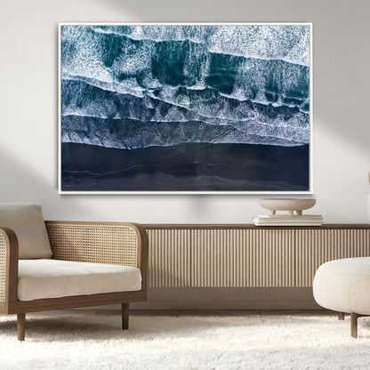 Canvas of aerial ocean waves crashing onto a black sand beach in moody tones, ideal for modern coastal or minimalist home decor.