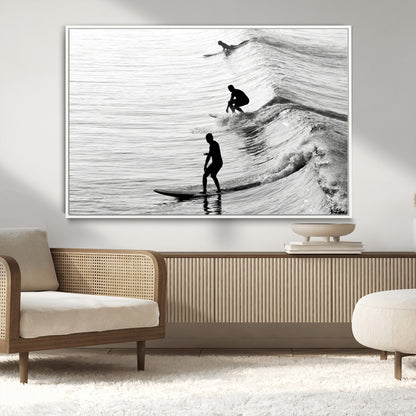 Black and white photo of surfers riding waves in a moody, high-contrast scene, ideal for modern coastal or surf-inspired home decor.