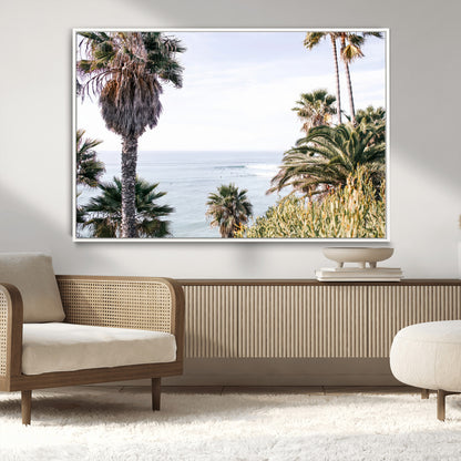 Scenic coastal view with tall palm trees overlooking a calm ocean, soft blue waves, and surfers in the distance, creating a peaceful tropical vibe.