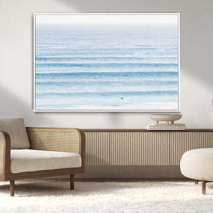 Minimalist ocean view with soft blue waves and a lone surfer, creating a serene and airy coastal aesthetic, perfect for tranquil home decor.