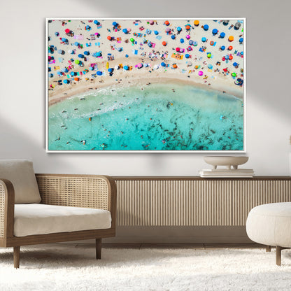Aerial view of a vibrant beach filled with colorful umbrellas and people enjoying the turquoise ocean, capturing a lively summer vacation scene.