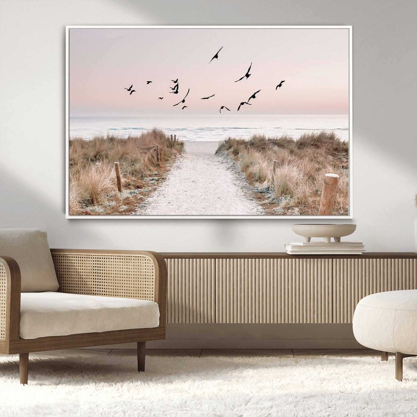 A peaceful coastal pathway leading to the ocean, with birds flying across a soft pastel sky, creating a calm and scenic beach atmosphere.