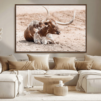 Texas Longhorn bull resting on dusty ground with warm tones, ideal for rustic western or farmhouse-themed wall decor.
