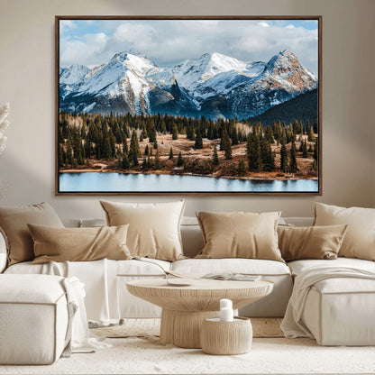 Framed canvas of snowy mountain peaks with pine forest and alpine lake, perfect for winter cabin or wilderness-inspired home decor.