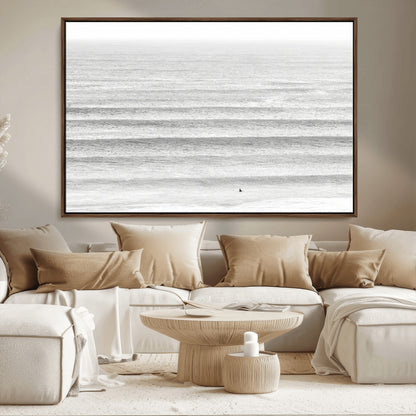 Monochrome photo of a lone surfer in calm layered waves, perfect for minimalist coastal or moody ocean-inspired wall decoration.