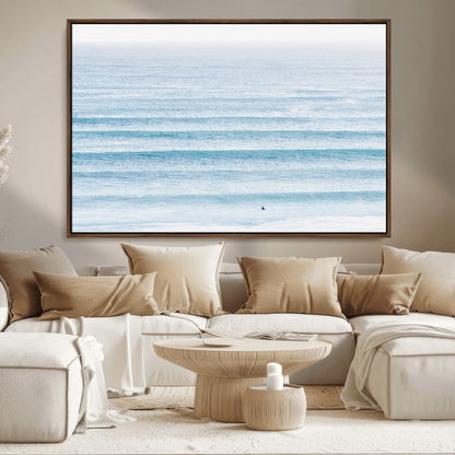 Minimalist ocean view with soft blue waves and a lone surfer, creating a serene and airy coastal aesthetic, perfect for tranquil home decor.