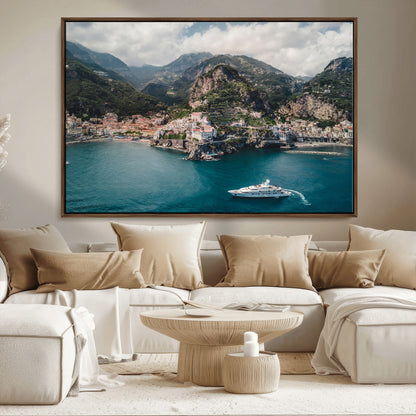 Aerial view of Amalfi Coast, Italy, with colorful hillside houses, lush green mountains, and a luxury yacht sailing in turquoise waters.