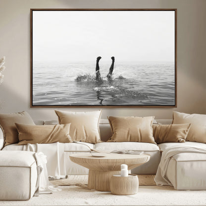 A black and white minimalist water scene capturing a playful splash as a swimmer dives upside down, creating a carefree and artistic aquatic aesthetic.