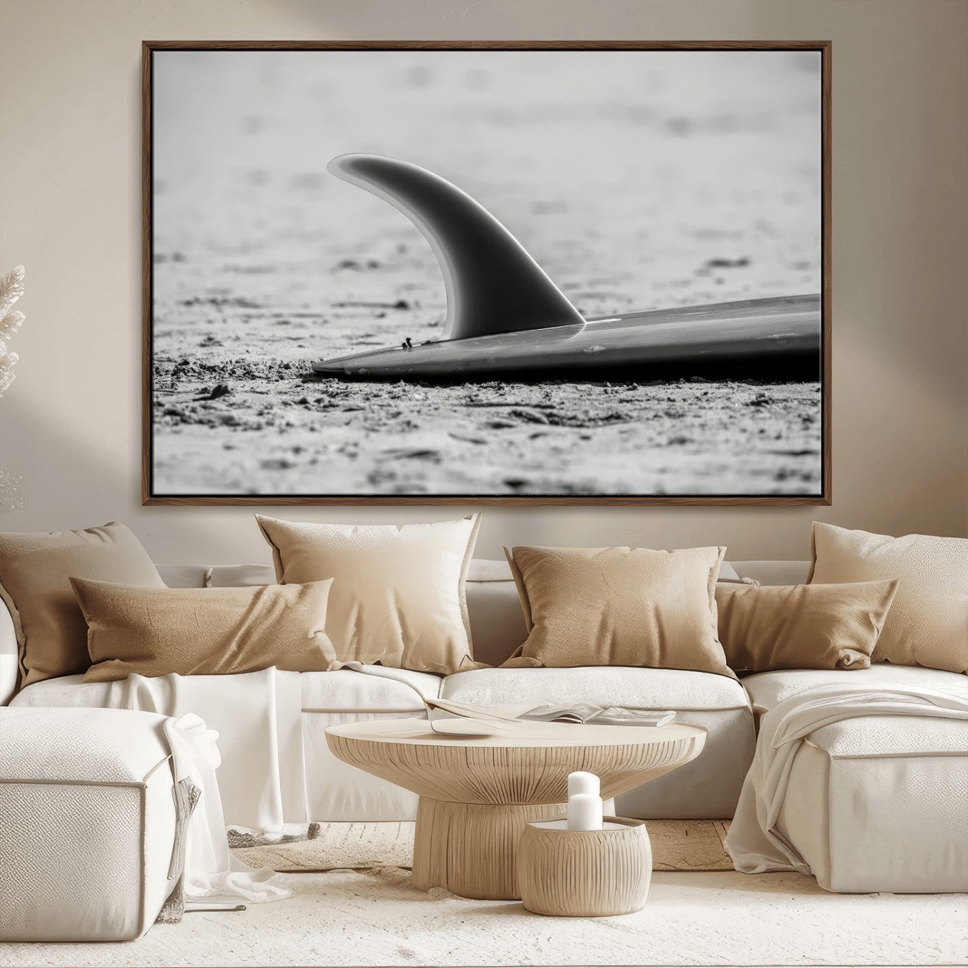 A black and white close-up of a surfboard fin resting on the sandy shore, highlighting minimalist beach aesthetics and classic surf culture.