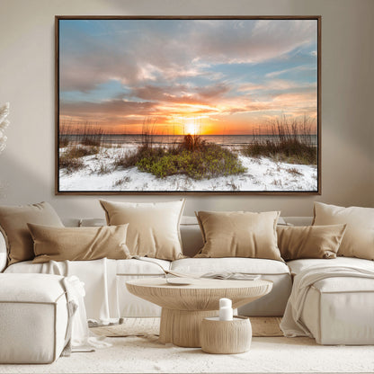 A tranquil beach scene featuring golden sunset hues over the water, with grasses in the foreground and a peaceful, serene atmosphere.